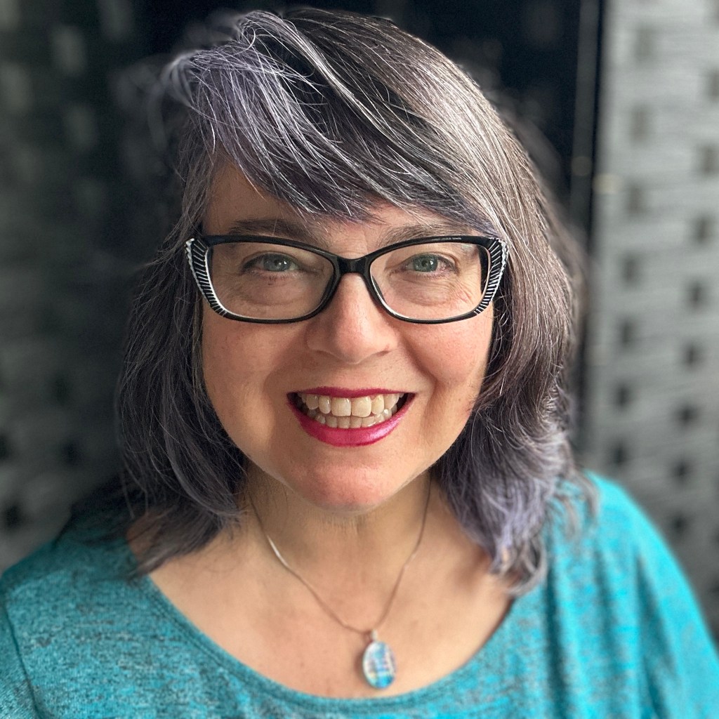 Izolda wearing turquoise top facing camera and with dark gray background